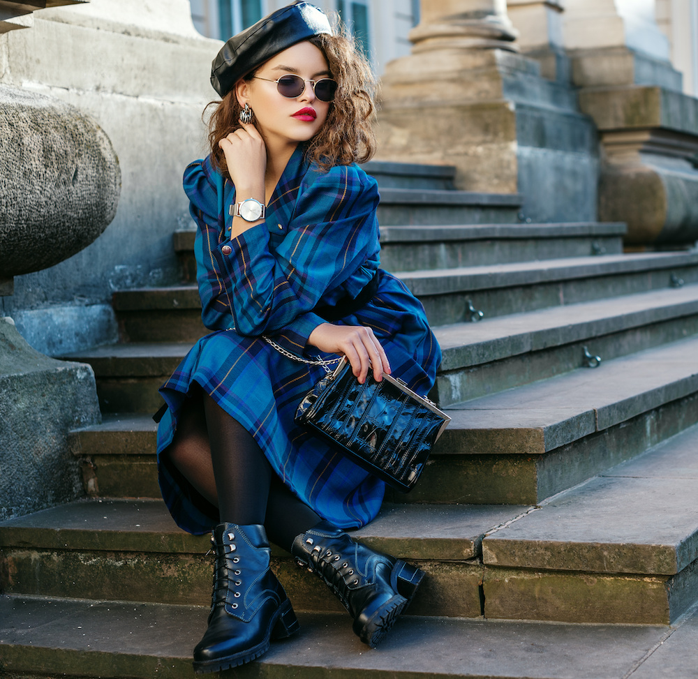 Pretty redhead wearing a royal blue patterned coat with cap and boots.