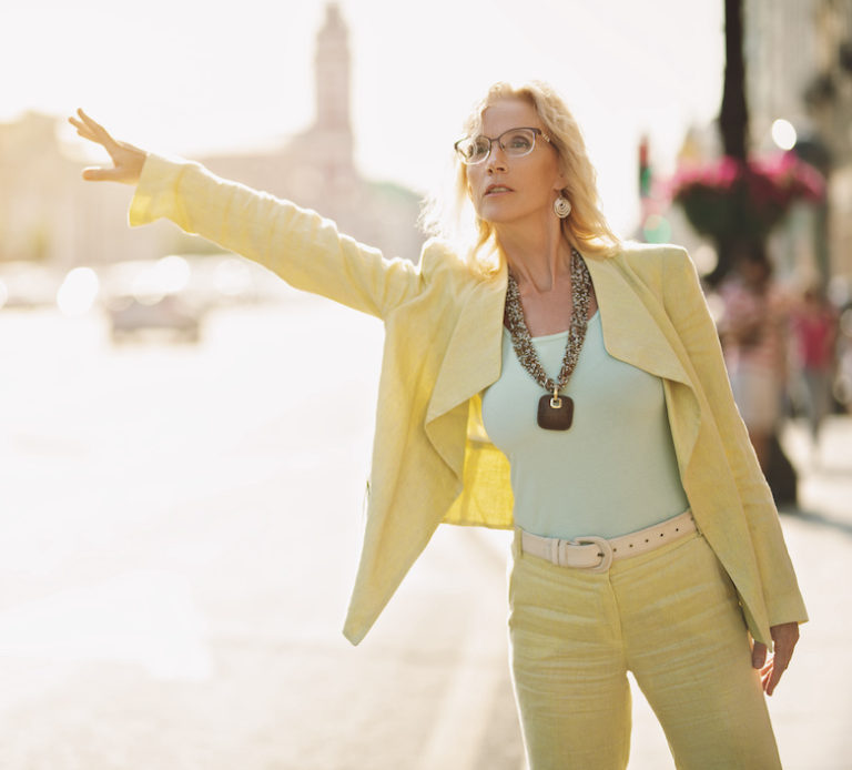 A portrait of a stylish woman in the street trying to catch a taxi.